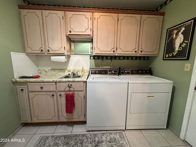 clothes washing area with cabinets, washing machine and dryer, light tile patterned floors, and sink