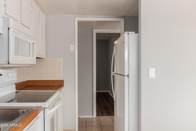 kitchen featuring sink, white cabinets, white appliances, backsplash, and light tile patterned floors