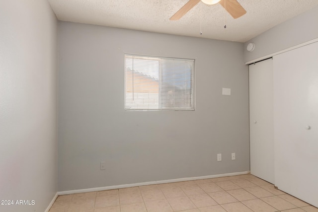 tiled empty room featuring ceiling fan and a textured ceiling