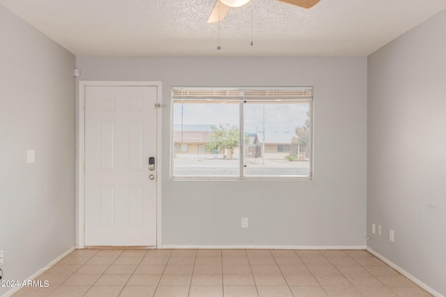 entryway featuring a textured ceiling, light tile patterned floors, and ceiling fan