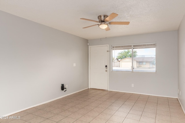 spare room with ceiling fan, light tile patterned flooring, and a textured ceiling