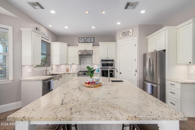 kitchen with visible vents, stainless steel appliances, a large island, under cabinet range hood, and a kitchen breakfast bar