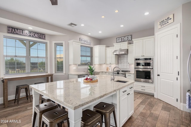 kitchen featuring visible vents, backsplash, under cabinet range hood, double oven, and a sink