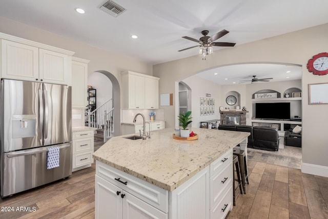 kitchen with a sink, stainless steel fridge, arched walkways, and light wood-style flooring