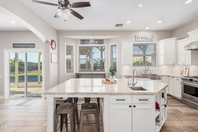 kitchen with visible vents, white cabinets, stainless steel gas range, and a sink