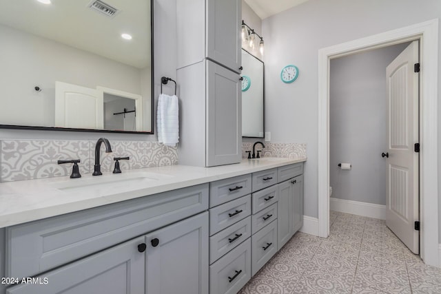 bathroom featuring a sink, visible vents, double vanity, and decorative backsplash