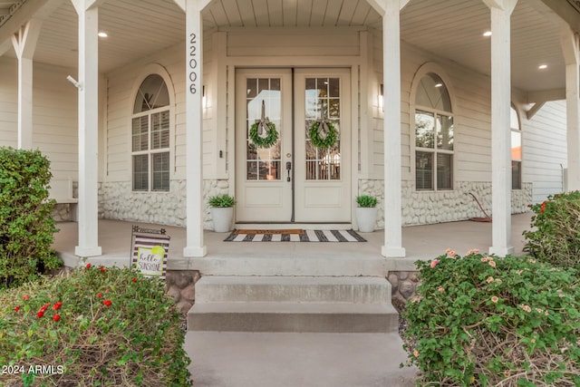 view of exterior entry with stone siding and a porch