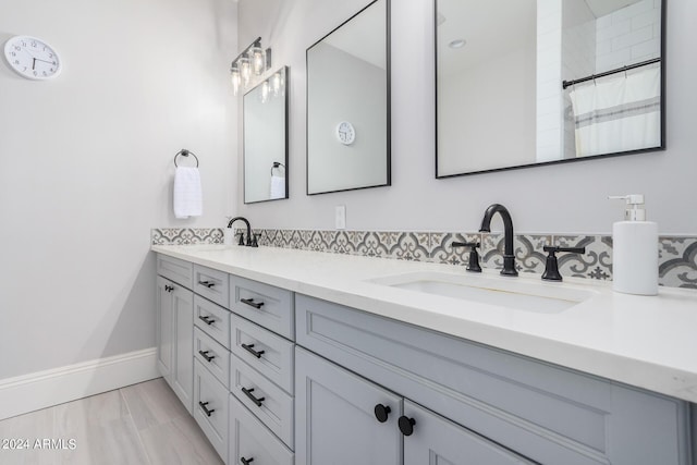 bathroom with double vanity, curtained shower, baseboards, and a sink