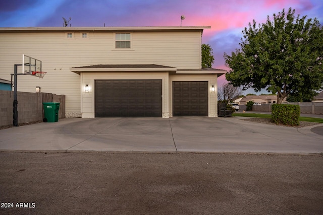 view of front of home featuring an attached garage, concrete driveway, and fence