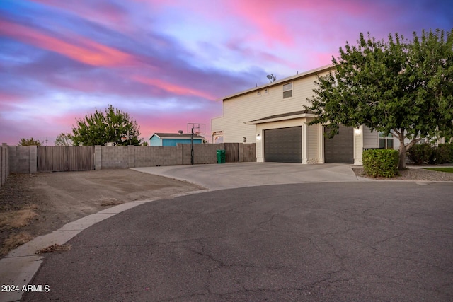 property exterior at dusk with fence and a garage