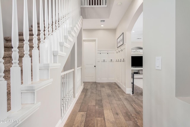 hall with recessed lighting, wood finished floors, visible vents, and arched walkways