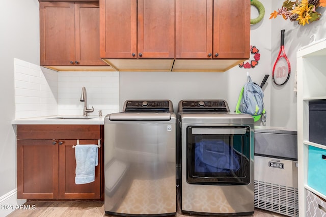 clothes washing area with a sink, cabinet space, and separate washer and dryer