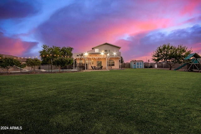 back of house with an outdoor structure, a playground, a fenced backyard, and a shed