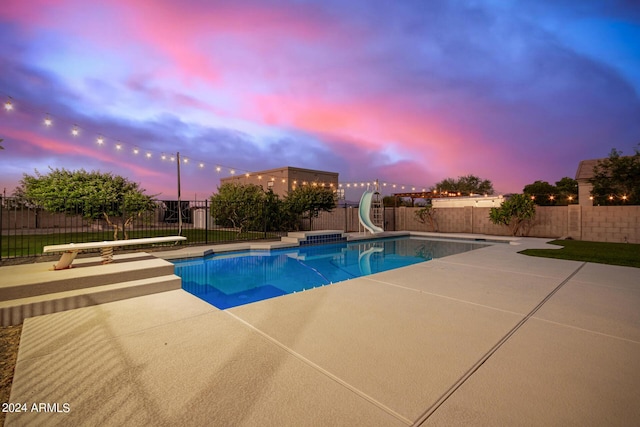 pool at dusk featuring a fenced in pool, a water slide, a fenced backyard, and a patio area