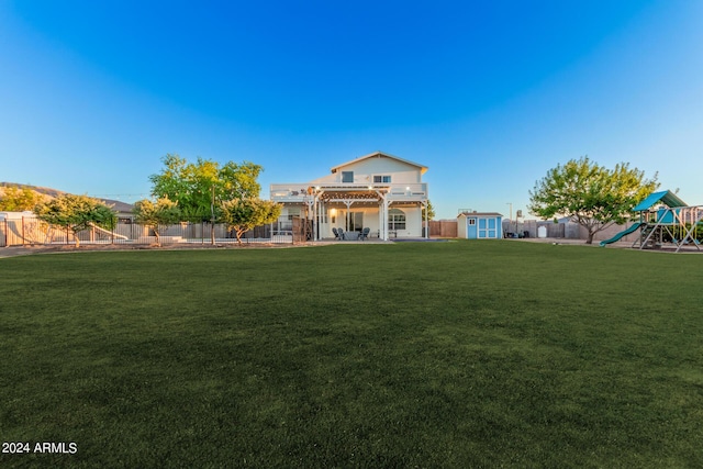 exterior space with a playground, a lawn, a fenced backyard, an outbuilding, and a storage unit