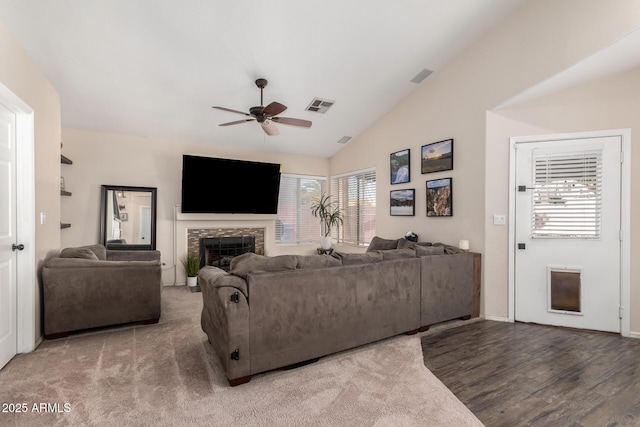 living room with a fireplace, lofted ceiling, visible vents, ceiling fan, and wood finished floors