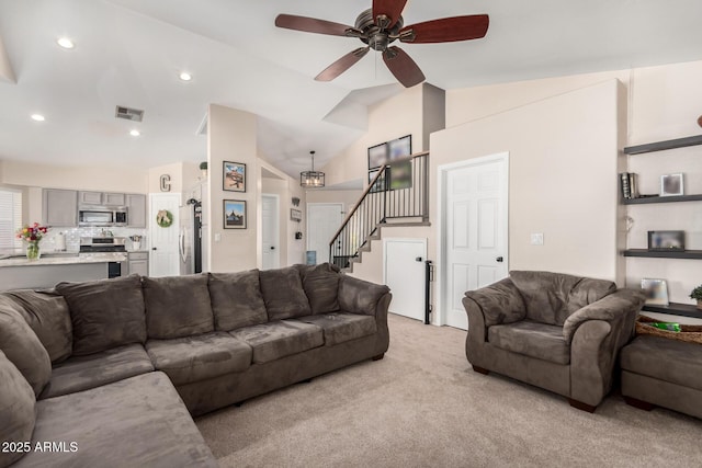 living area with ceiling fan, light carpet, visible vents, vaulted ceiling, and stairway