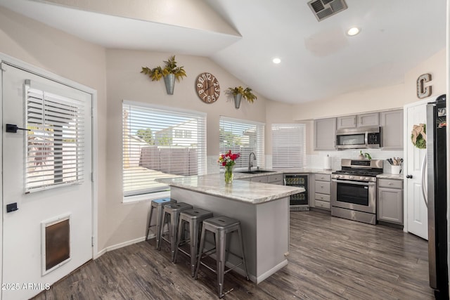 kitchen featuring a breakfast bar area, visible vents, appliances with stainless steel finishes, a sink, and a peninsula