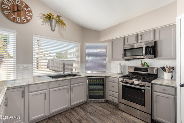 kitchen with gray cabinets, decorative backsplash, appliances with stainless steel finishes, a sink, and beverage cooler