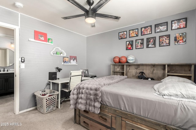 bedroom featuring ceiling fan, light colored carpet, a sink, baseboards, and ensuite bath