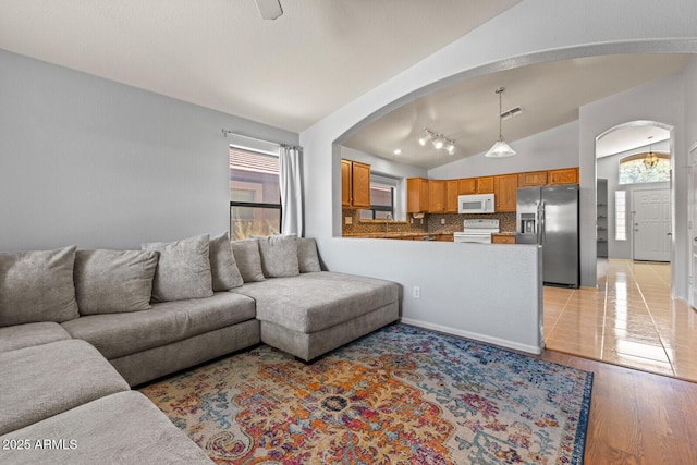 878 E Mountain View Rd, San Tan Valley, AZ 85143 - living room featuring arched walkways, vaulted ceiling, healthy amount of natural light, and light wood-style flooring