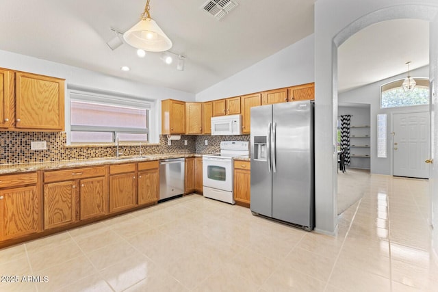 878 E Mountain View Rd, San Tan Valley, AZ 85143 - kitchen featuring appliances with stainless steel finishes, lofted ceiling, tasteful backsplash, brown cabinets, and decorative light fixtures