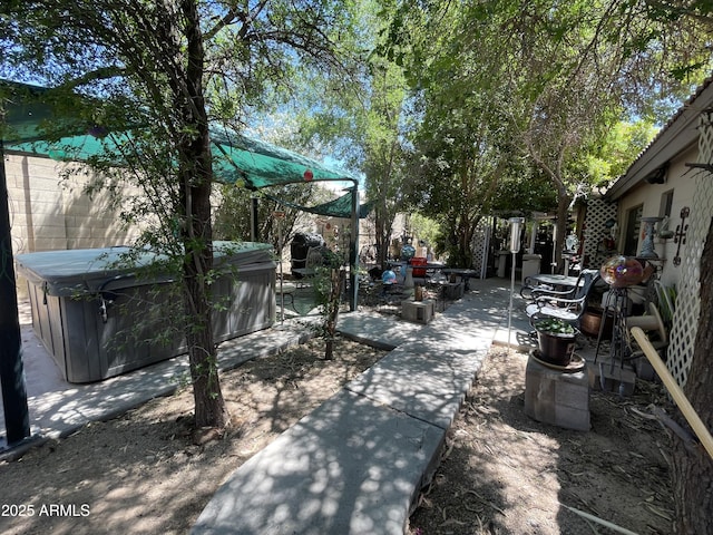 view of patio with a hot tub and fence