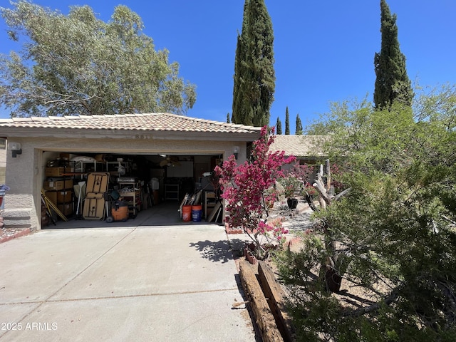 exterior space featuring a garage, a tile roof, and concrete driveway