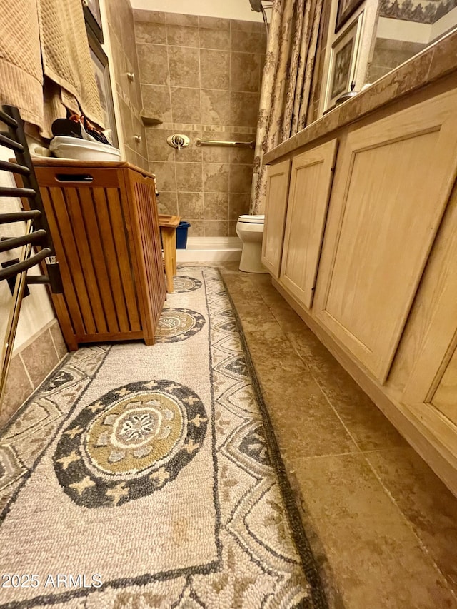 full bathroom featuring toilet, tiled shower, and tile walls