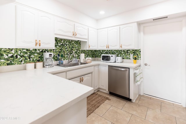 kitchen featuring stainless steel dishwasher, white cabinetry, and sink