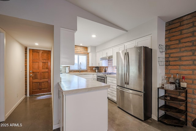 kitchen featuring appliances with stainless steel finishes, tasteful backsplash, white cabinetry, sink, and concrete floors