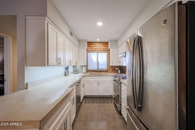 kitchen featuring sink, appliances with stainless steel finishes, white cabinetry, light stone counters, and kitchen peninsula