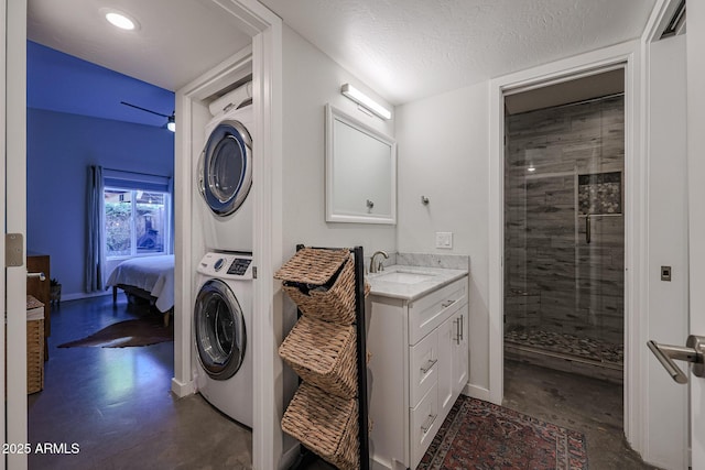 clothes washing area featuring stacked washer and dryer, sink, and a textured ceiling