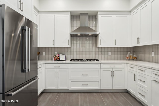 kitchen with white cabinets, high quality fridge, wall chimney exhaust hood, and gas stovetop