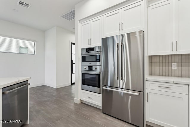 kitchen featuring white cabinets, appliances with stainless steel finishes, decorative backsplash, and visible vents