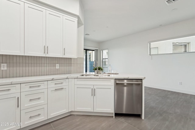 kitchen featuring tasteful backsplash, dishwasher, a sink, white cabinets, and a peninsula