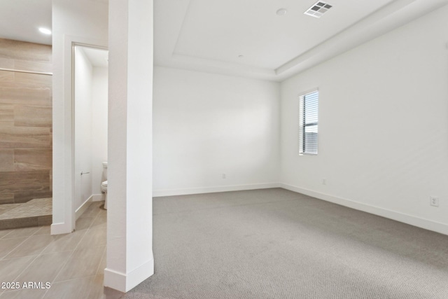 carpeted spare room featuring baseboards and visible vents