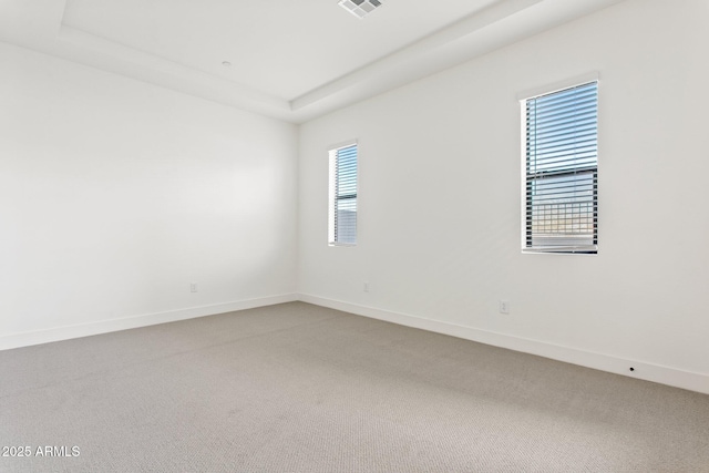 spare room with carpet floors, baseboards, visible vents, and a healthy amount of sunlight