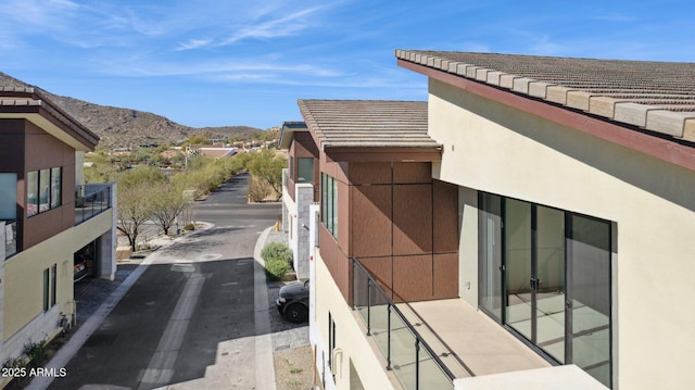 view of side of property featuring a tiled roof, a mountain view, and stucco siding