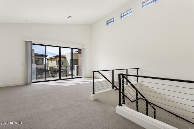 carpeted empty room with baseboards, a wealth of natural light, and high vaulted ceiling
