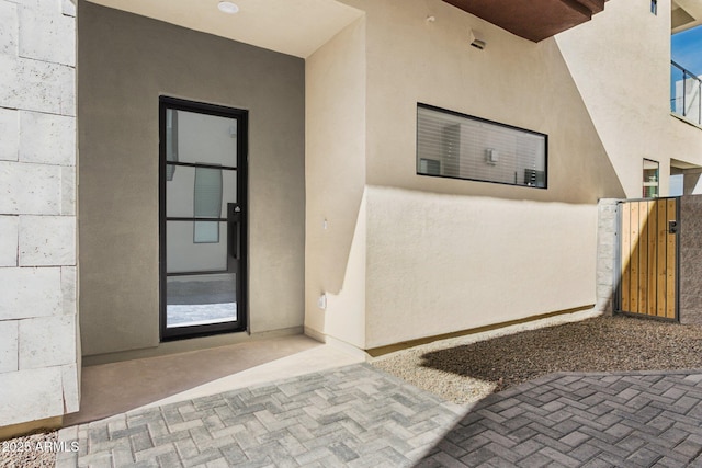 doorway to property with a gate and stucco siding