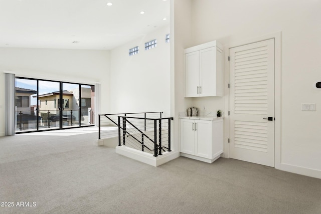 spare room with light colored carpet, recessed lighting, baseboards, and high vaulted ceiling