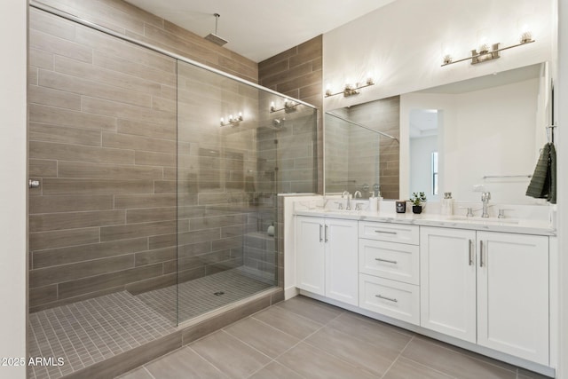 bathroom with double vanity, a sink, tile patterned flooring, and a stall shower