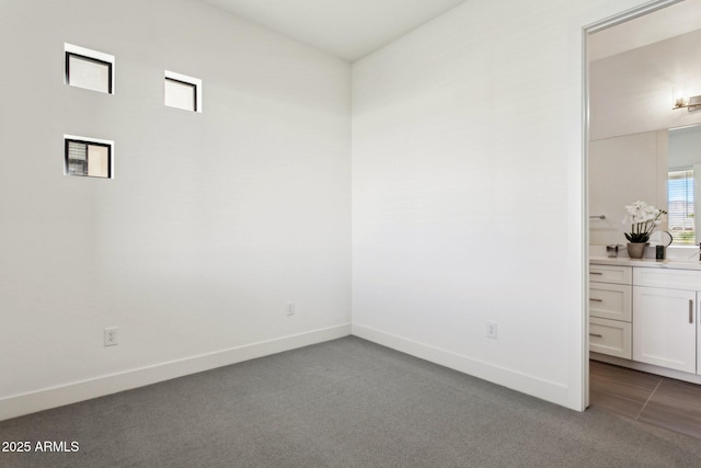 spare room featuring dark carpet and baseboards