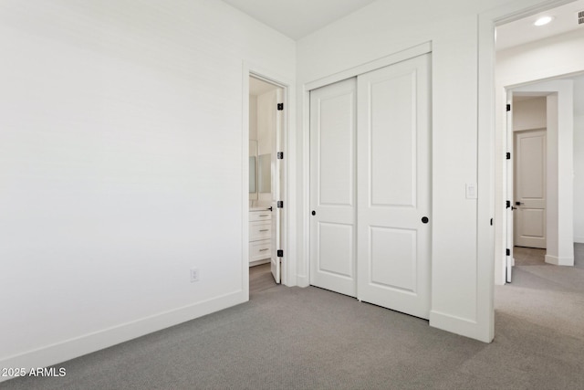 unfurnished bedroom with carpet flooring, baseboards, ensuite bathroom, visible vents, and a closet