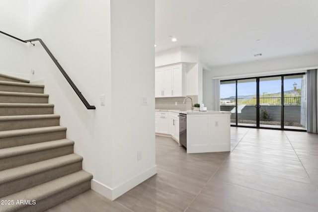 kitchen featuring light countertops, white cabinetry, baseboards, backsplash, and stainless steel dishwasher
