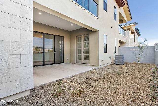 rear view of house with fence, cooling unit, a patio area, and stucco siding
