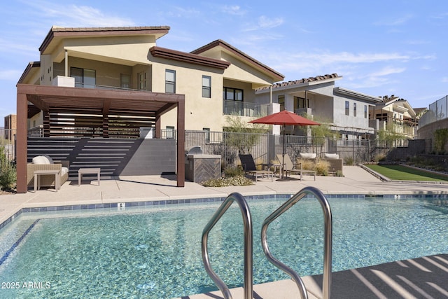 rear view of property featuring a community pool, a patio, fence, and stucco siding