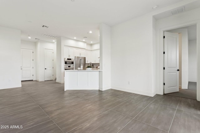 unfurnished living room featuring visible vents, recessed lighting, and baseboards