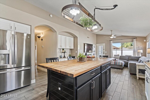 kitchen featuring white cabinets, wood counters, a kitchen island, and stainless steel refrigerator with ice dispenser